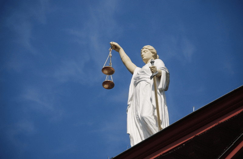 scales of justice statue on roof of building