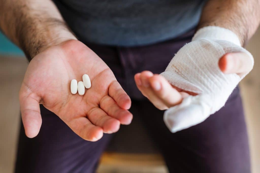 man with injured hand wrapped in a bandage holding medication