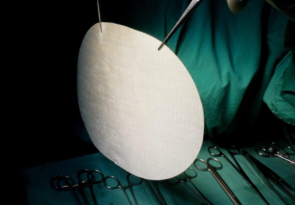 hernia mesh composite mesh implant held up by surgeon tools